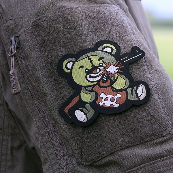 446102 10019 Embleem stof fijn geweven Terreur Teddy groen 71441 <big>Zeer fijn geweven embleem van 100% stof met klittenband achterzijde.  </big> <big>Door de fijne weving is dit embleem zeer gedetailleerd.</big>