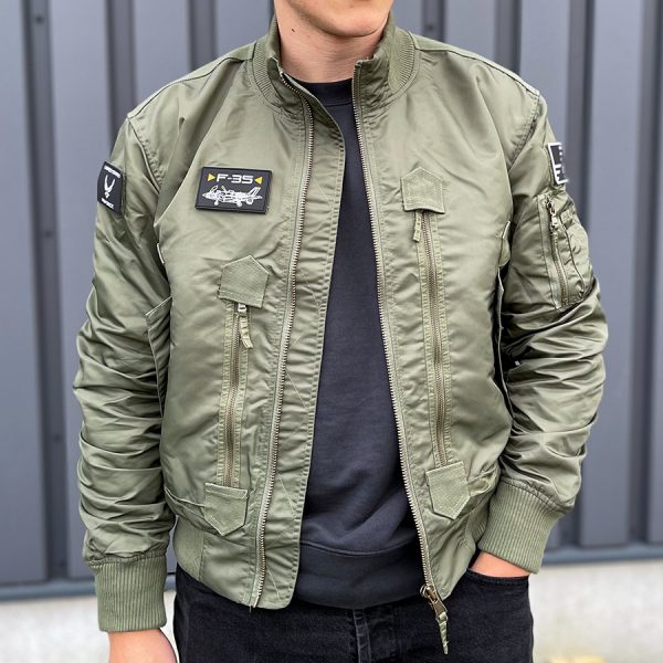 121425 F 35 Flight Jacket1 De F-35 Flight Jacket is niet zomaar een bomberjack; het is een symbool van functionaliteit, stijl en duurzaamheid. Gemaakt van hoogwaardig 100% nylon, is dit tactical bomberjack ontworpen om je warm en comfortabel te houden in diverse omstandigheden. De polyester voering voegt extra warmte toe, waardoor dit jack ideaal is voor het tussenseizoen of als tussenlaag tijdens koude dagen. De jas sluit mooi aan op het lichaam dankzij de elastische boorden en mouwen, wat zorgt voor een comfortabele pasvorm en extra bescherming tegen de elementen. Maar dit jack biedt niet alleen comfort; het voegt ook stijl toe aan je look. Het tijdloze ontwerp van een bomberjack is zowel functioneel als trendy, en het past naadloos in het huidige straatbeeld. Het F-35 Flight Jacket is voorzien van handige details, zoals de sterke YKK hoofdrits, elastische boorden en mouwen, een elastische kraag en geventileerde oksels voor extra ademend vermogen. De jas heeft veel opbergruimte met twee steekzakken, twee ritszakken en zelfs een opbergvakje met rits en pennenvak op de linkermouw. Om het nog specialer te maken, wordt dit jack geleverd met 3 PVC patches met een Airforce thema, waardoor het een unieke uitstraling heeft. Kortom, het F-35 Flight Jacket is de perfecte combinatie van functionaliteit, stijl en duurzaamheid. Kies voor dit jack en wees klaar voor avontuur, zowel in de natuur als in de stad. <strong>Kenmerken:</strong> <ul> <li><big>Sterke YKK hoofdrits</big></li> <li><big>Inclusief 3 PVC patches (Airforce)</big></li> <li><big>Elastische boorden (onderzijde & mouwen)</big></li> <li><big>Elastische naad in de mouwen </big></li> <li><big>Elastische kraag </big></li> <li><big>Twee steekzakken met klittenband sluiting</big></li> <li><big>Twee ritszakken met veel opbergruimte</big></li> <li><big>Linkermouw voorzien van opbergvakje met rits en pennenvak</big></li> <li><big>Geventileerde oksels</big></li> </ul> <a title="Maattabel" href="https://dump.dev.newagents.nl/wp-content/uploads/2021/11/121425-F-35-Flight-Jacket.pdf" target="_blank" rel="noopener noreferrer"><button><span style="color: #ef471f; font-size: medium;"><strong>Maattabel</strong></span></button></a>