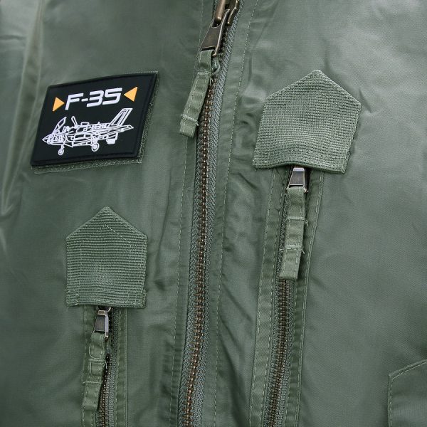 121425 F 35 Flight Jacket4 De F-35 Flight Jacket is niet zomaar een bomberjack; het is een symbool van functionaliteit, stijl en duurzaamheid. Gemaakt van hoogwaardig 100% nylon, is dit tactical bomberjack ontworpen om je warm en comfortabel te houden in diverse omstandigheden. De polyester voering voegt extra warmte toe, waardoor dit jack ideaal is voor het tussenseizoen of als tussenlaag tijdens koude dagen. De jas sluit mooi aan op het lichaam dankzij de elastische boorden en mouwen, wat zorgt voor een comfortabele pasvorm en extra bescherming tegen de elementen. Maar dit jack biedt niet alleen comfort; het voegt ook stijl toe aan je look. Het tijdloze ontwerp van een bomberjack is zowel functioneel als trendy, en het past naadloos in het huidige straatbeeld. Het F-35 Flight Jacket is voorzien van handige details, zoals de sterke YKK hoofdrits, elastische boorden en mouwen, een elastische kraag en geventileerde oksels voor extra ademend vermogen. De jas heeft veel opbergruimte met twee steekzakken, twee ritszakken en zelfs een opbergvakje met rits en pennenvak op de linkermouw. Om het nog specialer te maken, wordt dit jack geleverd met 3 PVC patches met een Airforce thema, waardoor het een unieke uitstraling heeft. Kortom, het F-35 Flight Jacket is de perfecte combinatie van functionaliteit, stijl en duurzaamheid. Kies voor dit jack en wees klaar voor avontuur, zowel in de natuur als in de stad. <strong>Kenmerken:</strong> <ul> <li><big>Sterke YKK hoofdrits</big></li> <li><big>Inclusief 3 PVC patches (Airforce)</big></li> <li><big>Elastische boorden (onderzijde & mouwen)</big></li> <li><big>Elastische naad in de mouwen </big></li> <li><big>Elastische kraag </big></li> <li><big>Twee steekzakken met klittenband sluiting</big></li> <li><big>Twee ritszakken met veel opbergruimte</big></li> <li><big>Linkermouw voorzien van opbergvakje met rits en pennenvak</big></li> <li><big>Geventileerde oksels</big></li> </ul> <a title="Maattabel" href="https://dump.dev.newagents.nl/wp-content/uploads/2021/11/121425-F-35-Flight-Jacket.pdf" target="_blank" rel="noopener noreferrer"><button><span style="color: #ef471f; font-size: medium;"><strong>Maattabel</strong></span></button></a>