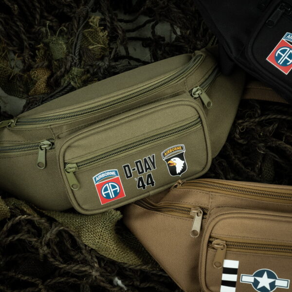 359395 Heuptas D Day 1944 Airborne2 De D-Day 1944 Airborne Heuptas Groen is een eerbetoon aan de historische gebeurtenissen van D-Day en de legendarische Airborne Division. Maar het is niet alleen een eerbetoon; het is ook een uiterst functionele heuptas. Met vijf verschillende vakken, elk beveiligd met een duurzame ritssluiting, biedt deze heuptas voldoende opbergruimte voor al je belangrijke spullen. Of je nu onderweg bent naar een reisavontuur of een levendig festival, deze tas helpt je om je geld, pasjes en andere benodigdheden veilig en georganiseerd te houden. De verstelbare band met gespsluiting zorgt ervoor dat je de tas comfortabel om je middel kunt dragen, ongeacht je lichaamsvorm of kledingkeuze. Het materiaal van 100% polyester is duurzaam en gemakkelijk schoon te houden. Met de D-Day 1944 Airborne Heuptas ben je niet alleen goed georganiseerd, maar draag je ook een stukje geschiedenis met je mee. <strong><big>Kenmerken:</big></strong> <ul> <li><big>Materiaal: 100% polyester</big></li> <li><big>Verstelbare band met gespsluiting</big></li> <li><big>Vijf vakken met een ritssluiting</big></li> </ul>